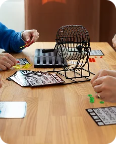 Ludzie grają w bingo przy drewnianym stole.